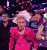 a woman in a pink dress is standing in front of a crowd .