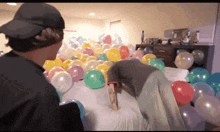 a person laying on a bed surrounded by balloons including one that says " i love you "