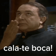 a man in a black shirt is making a funny face with the words cala-te boca below him
