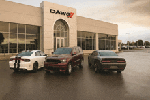 three vehicles are parked in front of a dawg dealership