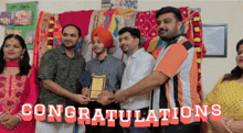 a group of people standing in front of a wall that says congratulations on it