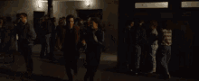 a man and a woman are walking through a crowd of people in a dark room .