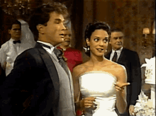 a man in a tuxedo stands next to a woman in a white dress