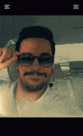 a man with a beard and mustache wearing sunglasses is sitting in a car