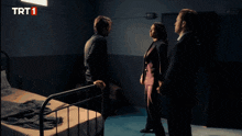three people standing in a dark room with trt1 written on the bottom left