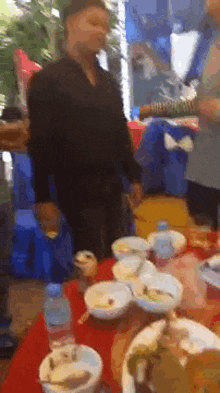 a man is standing in front of a table full of bowls and plates of food