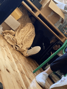 a person is hiding under a desk with a blanket and a box on it
