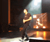 a man wearing a black shirt with the letter a on it is dancing on a stage