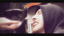 a man wearing a black hooded sweatshirt looks down