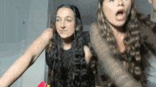 two women are standing next to each other with their mouth open