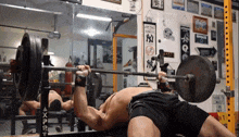 a man lifting a barbell in a gym with a ny yankees banner on the wall behind him