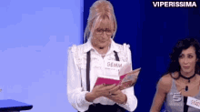 a woman in glasses is reading a book while another woman looks on .
