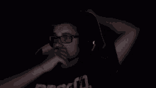 a blurry picture of a man wearing glasses and a black shirt in the dark .