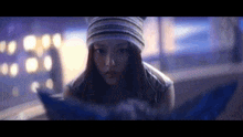 a woman wearing a hat and a scarf is looking at something in a dark room .