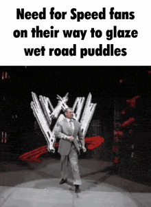 a man in a suit and tie is on a stage in front of a wwe logo