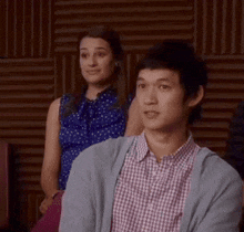 a man in a plaid shirt is sitting in front of a woman .