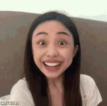 a woman is making a funny face and smiling while sitting on a couch .