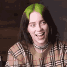 billie eilish is wearing a plaid sweater and a choker while smiling .