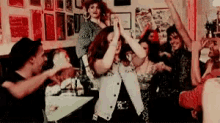 a group of people are dancing together in a room with their arms in the air .