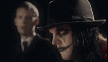 a man in a suit and tie stands next to a woman in a black hat
