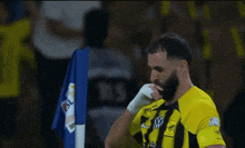 a man in a yellow and black striped jersey holds up a blue shirt