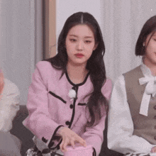 a woman in a pink jacket is sitting on a couch with another woman .