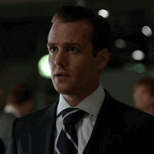 a man in a suit and tie stands in a crowd