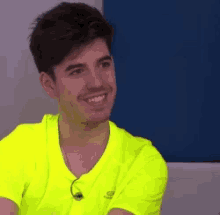 a man in a neon yellow shirt is smiling and looking to the side .