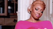 a woman in a pink dress is making a funny face while looking down .
