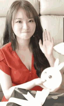 a woman in a red shirt is holding a stuffed bunny