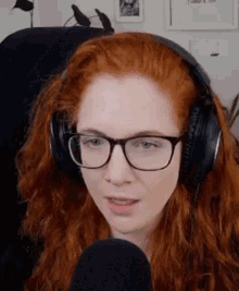 a woman with red hair is wearing headphones and glasses while talking into a microphone .
