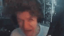 a man wearing headphones is making a funny face in front of a computer screen .