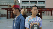 a man wearing a jimi hendrix tie dye shirt stands next to another man