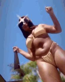 a woman in a yellow bikini is dancing in the sun .