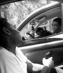 a man in a white shirt is holding a gun while sitting in a car