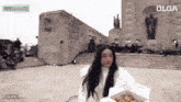 a woman holding a box of food in front of a building with the name olga on the bottom