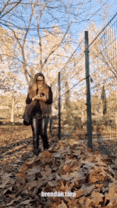 a woman standing in a pile of leaves with the name brendan tarp on the bottom right
