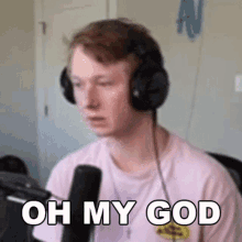 a man wearing headphones and a pink shirt is sitting in front of a microphone and saying oh my god .