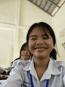 a girl in a white shirt with a blue lanyard around her neck that says ' a ' on it smiles