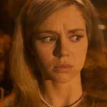 a close up of a woman wearing a pearl necklace and a headband