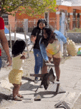 a little girl is standing next to a woman holding a piece of metal