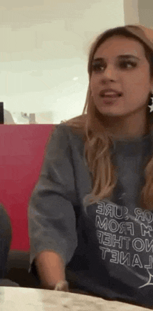 a woman is sitting at a table wearing a t-shirt that says `` i 'm sorry '' .