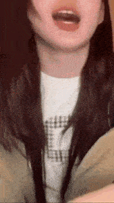 a close up of a woman 's face with her mouth open and a plaid shirt on .