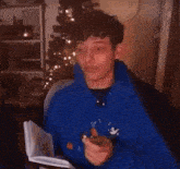 a man in a blue hoodie is holding a piece of paper and pointing