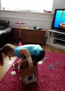 a little girl is squatting on a cardboard box that says ' nintendo ' on the front