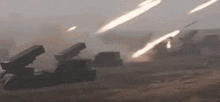 a group of missiles are being fired from a military vehicle in a field .