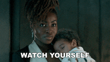 a woman holding a baby with the words watch yourself written below her
