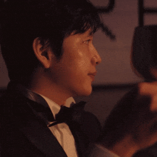 a man in a tuxedo holds a wine glass in his hand