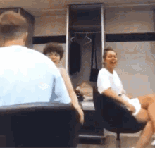 a group of people are sitting in chairs in front of a locker room laughing .