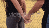 a woman is handcuffed by a police officer in front of a chain link fence and the words videohive are visible